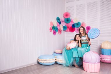 İki güzel kız mavi elbiseler eller büyük şeker ve Studio acıbadem kurabiyesi macaroons dekora tutun.