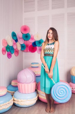 mavi elbiseli güzel kız elinde büyük şeker Studio dekor macaroons ile tutun. Kopya alanı.