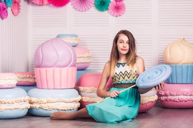 mavi elbiseli güzel kız elinde büyük şeker Studio dekor macaroons ile tutun. Kopya alanı.