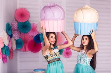 Mavi elbiseler iki güzel kızın ellerinde büyük kek Studio dekor macaroons ile tutun..