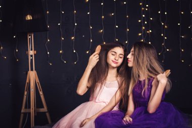 Neşeli kız. İki kız stüdyoda koyu arka plan üzerinde yan yana oturup birbirimizin saçını tarak. Kopya alanı