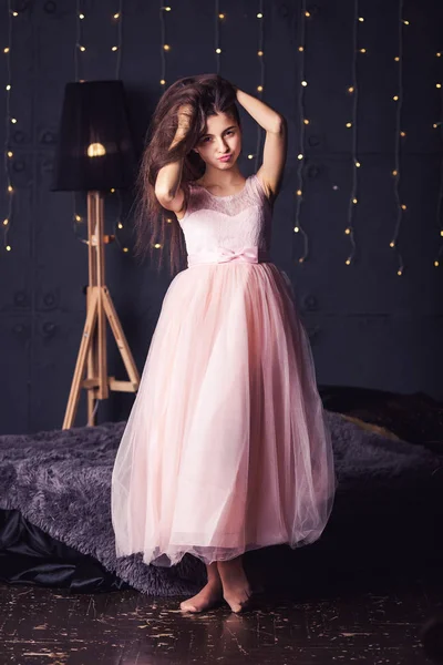 Chica de pelo largo en vestido rosa en estudio sobre fondo oscuro con bokeh. Copiar espacio . — Foto de Stock