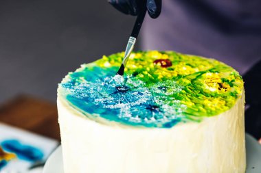 Şekerci pastayı renkli kremayla süsler. Desenli el yapımı kek..