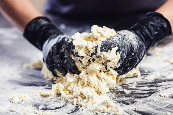 Baker's hands in black gloves knead the dough. — Stock Photo, Image