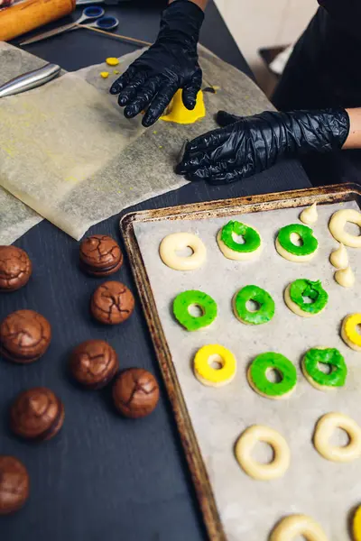 Cukrász díszíti nyers profiterolok zöld és sárga rövid tészta. — Stock Fotó