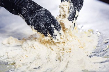 bakers hands in black gloves knead the dough.