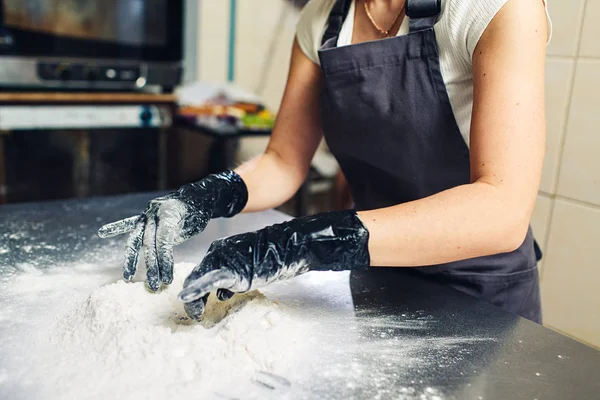 Les mains du boulanger en gants noirs pétrissent la pâte . — Photo