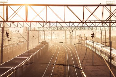 Yük vagonlu tren ve şafak vakti güneşli yolcu treni..