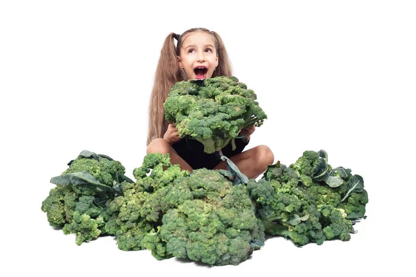 La niña sostiene y mora broccoli grande. aislado en blanco. Nutrición y hábitos alimenticios saludables para los niños concepto. vegano atunero niño. — Foto de Stock