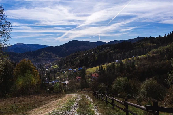 Paisaje otoñal: montañas carpáticas y pueblo de abajo, hermoso cielo con nubes de cirros.. — Foto de Stock