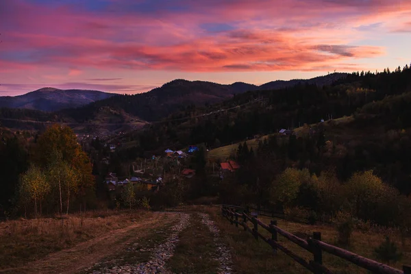 Bela paisagem montanhosa com céu iluminado por sol. estrada de saída com vista para a aldeia entre montanhas . — Fotografia de Stock
