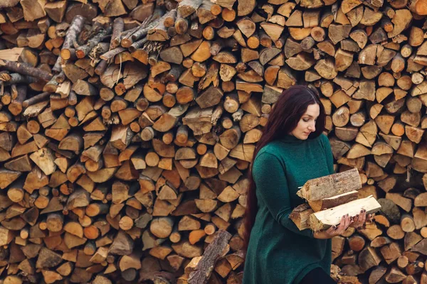 Длинноволосая девушка держит в руках сложенную дрова . — стоковое фото