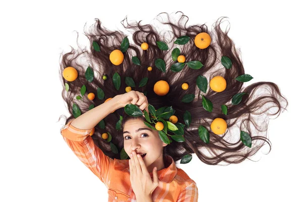 Jovencita guapa chica alegre se encuentra en el suelo con su cabello suelto en mandarinas y calamares. — Foto de Stock