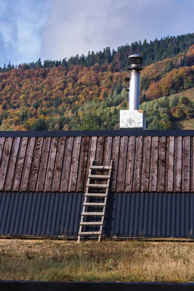 Toit avec escalier et cheminée d'acier contre ciel et montagnes. — Photo