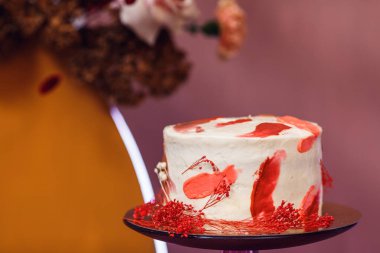 Düğün pastası, düğün kemerinin yanında, içinde çiçekler ve tuğla duvarlar var..