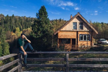 Sakallı iş adamı tırabzanda oturur, dizüstü bilgisayarda çalışır ve telefonda konuşur. Dağlarda tatilde olan serbest çalışan bir hippi.