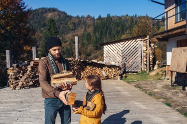 Kızım ve babam sonbaharda bahçede odun keserler.