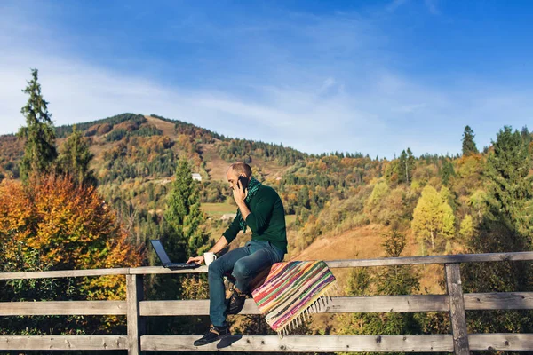 Skäggig Man Sitter Räcket Terrass Och Arbetar Laptop Samtal Telefon — Stockfoto