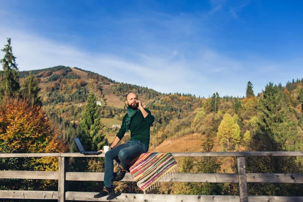 Skäggig Man Sitter Räcket Terrass Och Arbetar Laptop Samtal Telefon — Stockfoto