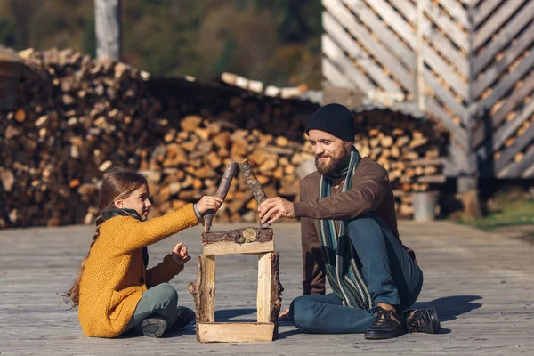 dad and daughter together build toy log house on outdoors on terrace