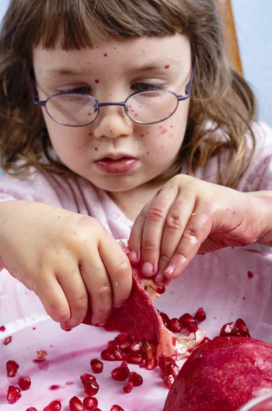 Giovane ragazza spremendo succo di melograno, facendo un pasticcio — Foto Stock