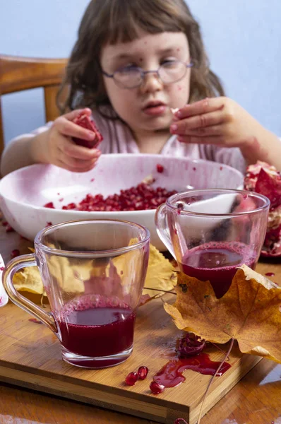 Giovane ragazza spremendo succo di melograno, facendo un pasticcio — Foto Stock