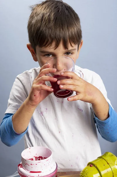 Fiatal fiú préselő és ivó gránátalma lé, így a rendetlenség — Stock Fotó