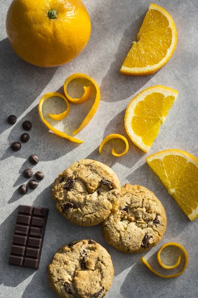 Chocolate chip and orange cookie. Orange peel in heart shape on grey stone background.