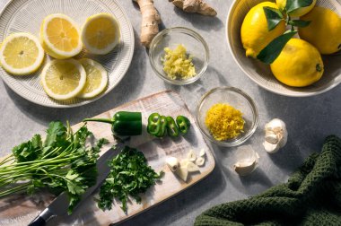Yaz malzemeleri, taze yeşil ve sarı baharatlar ve tatlar. Maydanoz, limon, sarımsak, yeşil biber ve zencefil. Güneşli bir masada köy manzarası. Alternatif tıp konsepti.