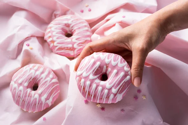 Женская Рука Организация Розовой Глазури Украшенные Пончики Волнистом Розовом Фоне — стоковое фото
