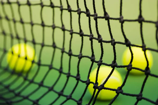Сеть тенниса в зеленом корте, три мяча на заднем плане — стоковое фото