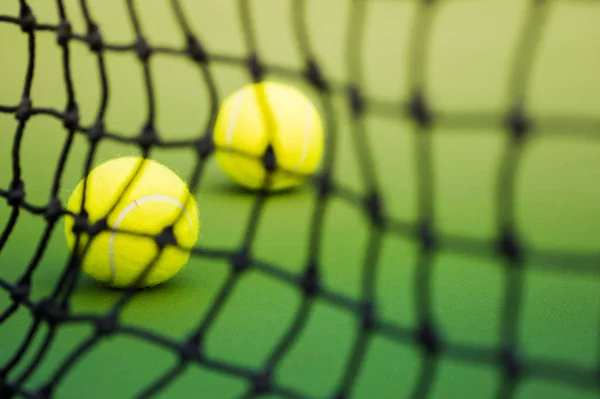 Δυο μπάλες του τένις στο Δικαστήριο πράσινο, μαύρο συνυφασμένη δίχτυ ως forground — Φωτογραφία Αρχείου