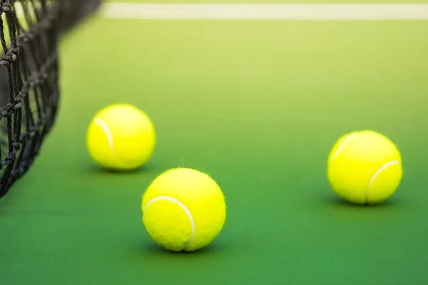 Три теннисных мяча на зеленом жестком корте — стоковое фото