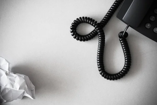 Black land line telephone and white crumpled paper on textured granite surface — Stock Photo, Image