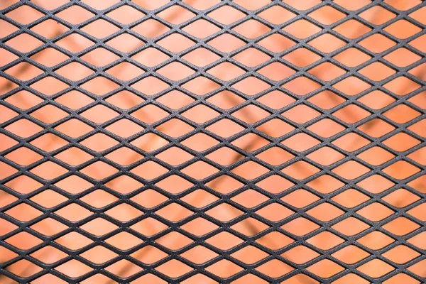 black expanded metal on blurred orange brick backgroud