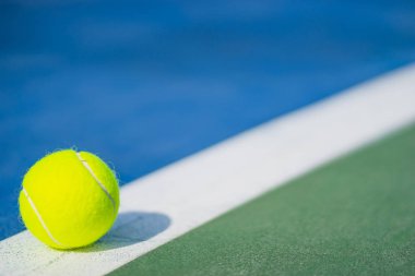 bir yeni tenis topu ile soldan ışık mavi ve yeşil sabit mahkemede beyaz çapraz çizgi üzerinde