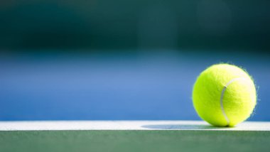 one new tennis ball on white line in blue and green hard court with light from right clipart