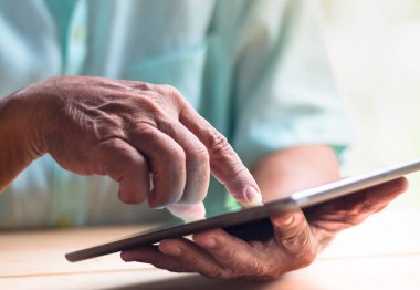yaşlı adam tablet sol el ile tutun ve dokunmatik ekran sağ işaret parmağı ile