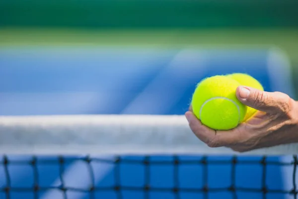 Oude Aziatische man houd twee tennisballen in de linkerhand, selectieve aandacht — Stockfoto