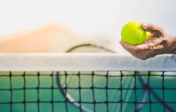 Ηλικίας ασιατικό άτομο κατέχει δύο μπάλες του τένις στο αριστερό χέρι — Φωτογραφία Αρχείου
