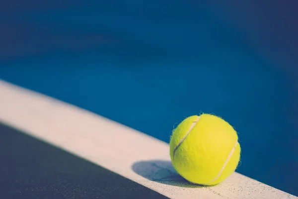 Une nouvelle balle de tennis sur la ligne diagonale blanche en cour dure bleue avec lumière de droite — Photo