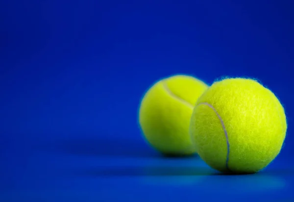 Zwei neue Tennisbälle auf blauem Platz mit Licht von rechts, Schatten und Kopierraum links — Stockfoto