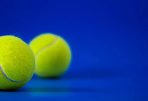 Duas novas bolas de tênis na quadra azul com luz da esquerda, sombra e espaço de cópia à direita — Fotografia de Stock