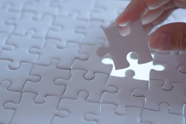 last piece of white plain jigsaw holding by hand, step of success concept clipart