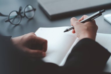 İş adamı ofisteki masanın üzerine not defteri, sonuç ve planlama konsepti yazar