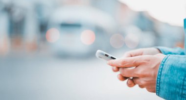 Asyalı adam arka planı bulanık şehir sokağında akıllı telefon kullanıyor.