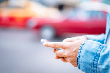 Asyalı adam arka planı bulanık şehir sokağında akıllı telefon kullanıyor.