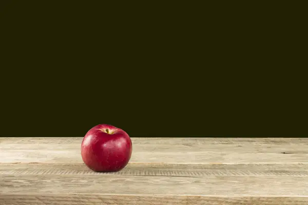 Красное яблоко на деревянном столе, черный фон — стоковое фото