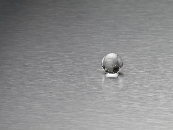 Glass ball on an aluminum background — Stock Photo, Image