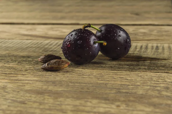 Um fruto de uma ameixa molhada em uma mesa de madeira — Fotografia de Stock